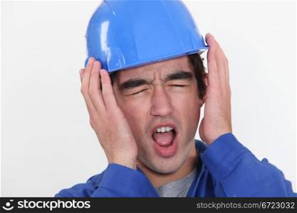A young manual worker hearing unbearable noise.