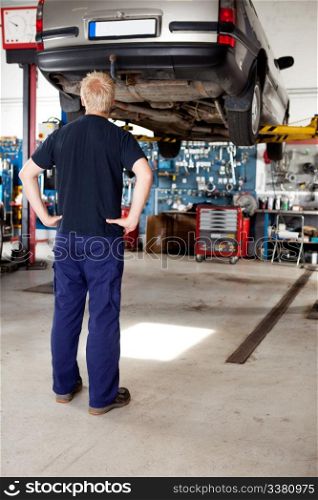 A young mechanic looking at a car that needs repair