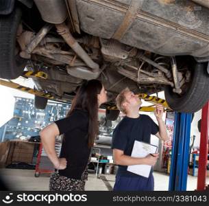 A young mechanic showing a female customer what was done to her car