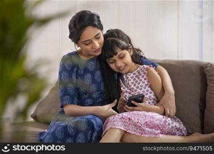 A YOUNG MOTHER AND DAUGHTER HAPPILY USING MOBILE PHONE 