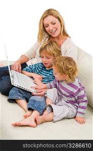 A young mother and her two children using a laptop at home on a settee