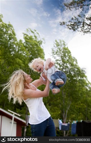 A young mother playing with excited toddler son, throwing him in the air.