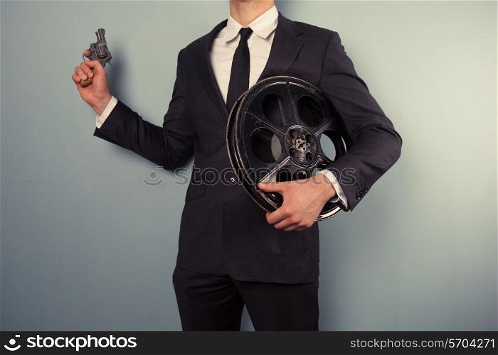 A young movie executive is holding a film reel and a gun