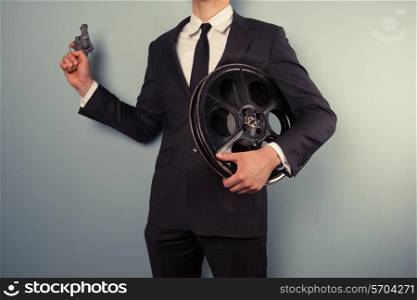 A young movie executive is holding a film reel and a gun
