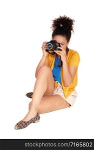 A young multi-racial woman sitting and taking some pictures with her camera, with her curly black hair, isolated for white background