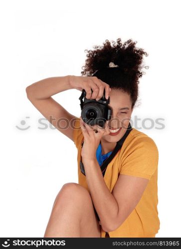 A young multi-racial woman sitting and taking some pictures with her camera, with her curly black hair focusing on the photographer, isolated for white background
