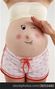 A young pregnant lady with a face drawing on her tummy