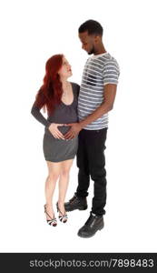 A young pregnant woman in a grey dress and red hear looking up toher man, an African American, isolated for white background.