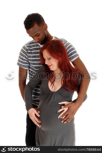 A young pregnant woman in a grey dress and red hear standing in front ofher man, an African American, isolated for white background.
