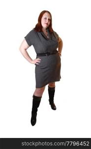 A young pretty full-figured woman in a gray dress and black boots, with brown red hair standing for white background