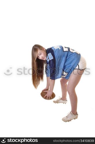 A young pretty girl in a football outfit and a football standing in the studiodemonstrating how to play, with long brunette hair for white background.