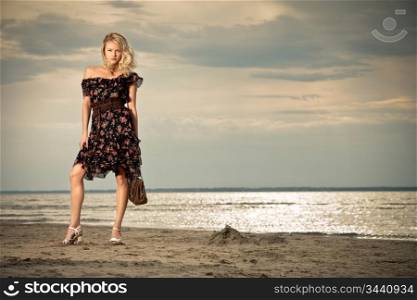A young pretty lady standing against the background of a seashore.