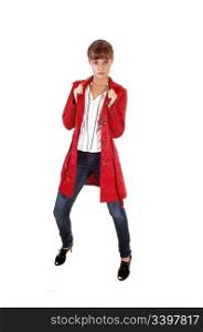 A young pretty teenager standing in a red winter coat an jeans in the studio, for white background.