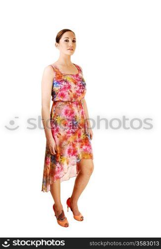 A young pretty woman in a colourful summer dress standing in the studiofor white background.