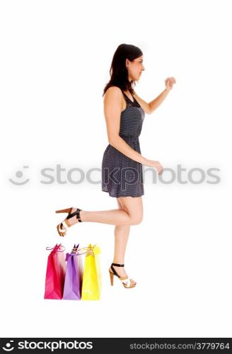 A young pretty woman in a grey dress standing beside her three shoppingbag&rsquo;s, isolated on white background.