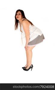 A young pretty woman in a short grey skirt and high heels standing isolatedfor white background, bending forwards.