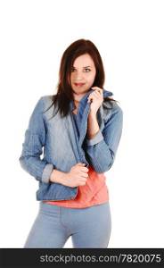 A young pretty woman in blue thighs, a pink t-shirt and blue jeans jacketstanding for white background, looking into the camera.