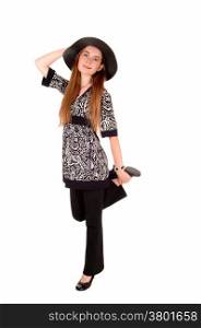 A young pretty woman in dress pants and a dress with a hat, standingisolated over white background.
