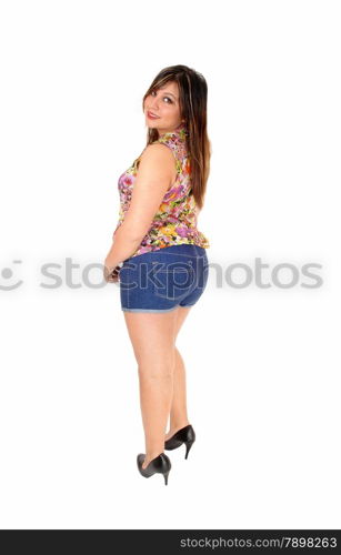 A young pretty woman in jeans shorts and heels standing from the backand looking over her shoulder, isolated for white background.