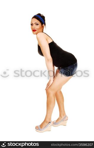 A young pretty woman in pin up style standing on the floor with shorts and highheels and a blue headband in her hair, for white background.