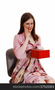 A young pretty woman sitting on a chair in a nice dress getting a redgift box for white background.