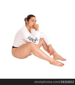 A young pretty woman sitting on the floor in a short white shirt, barefoot,isolated for white background.