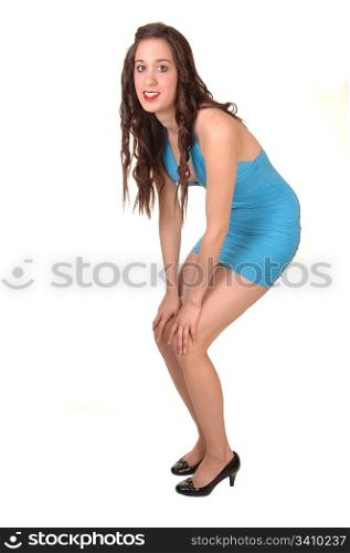 A young pretty woman standing in a short tight blue dress in thestudio, with her long brown hair, for white background.