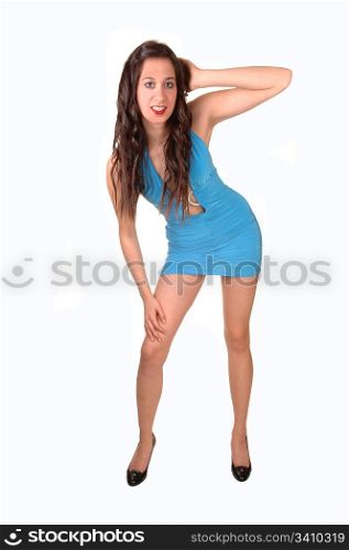 A young pretty woman standing in a short tight blue dress in thestudio, with her long brown hair, for white background.