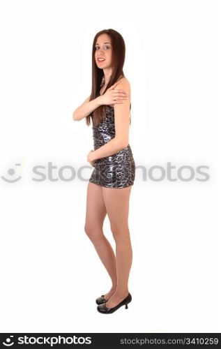 A young pretty woman standing in a short tight silver dress in thestudio, with her long brown hair, for white background.