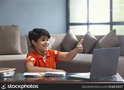 A YOUNG SCHOOL KID SHOWING THUMBS UP DURING ONLINE CLASS