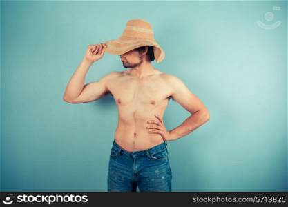 A young shirtless man is wearing a beach hat