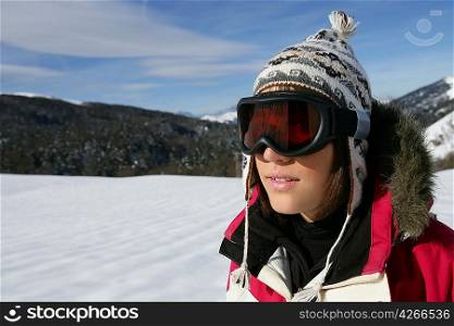A young skier wearing a pair of goggles on a sunny day