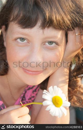 A young, smiling girl with a white flower