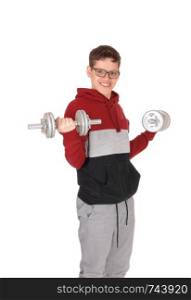 A young smiling teenager boy lifting up two dumbbells wearing a sweater and jeans, with glasses, isolated for white background