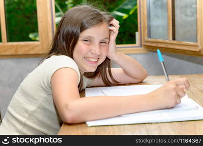 A young smiling teenager girl doing her homework