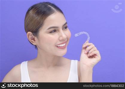 A young smiling woman holding invisalign braces in studio, dental healthcare and Orthodontic concept. . Young smiling woman holding invisalign braces in studio, dental healthcare and Orthodontic concept.