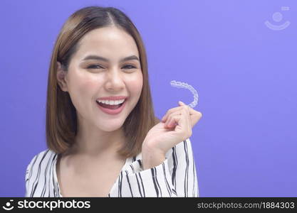 A young smiling woman holding invisalign braces in studio, dental healthcare and Orthodontic concept. . Young smiling woman holding invisalign braces in studio, dental healthcare and Orthodontic concept.