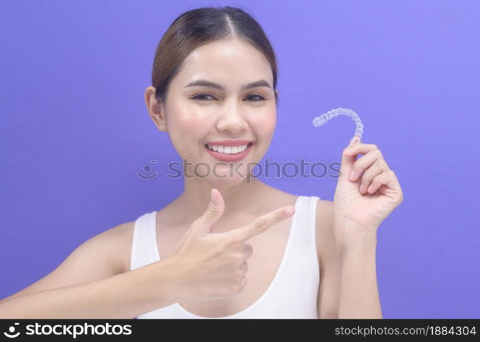 A young smiling woman holding invisalign braces in studio, dental healthcare and Orthodontic concept. . Young smiling woman holding invisalign braces in studio, dental healthcare and Orthodontic concept.