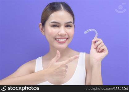 A young smiling woman holding invisalign braces in studio, dental healthcare and Orthodontic concept. . Young smiling woman holding invisalign braces in studio, dental healthcare and Orthodontic concept.
