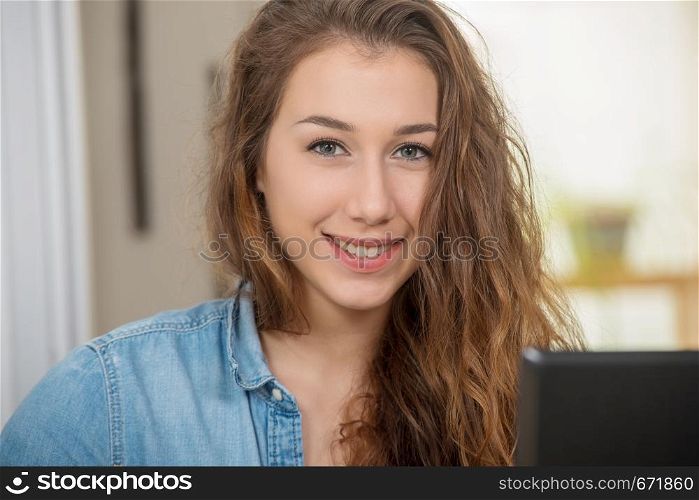 a young smiling woman with long hair is using a laptop