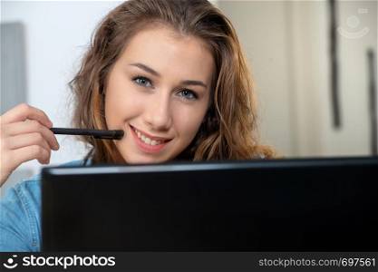 a young smiling woman with long hair is using a laptop