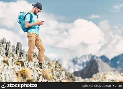 A young sportsman handles smart-phone during in alpine trek