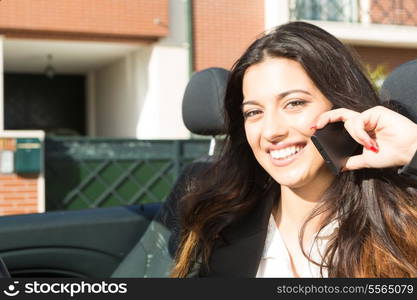 A young successful business woman at the phone in her brand new convertible sports car