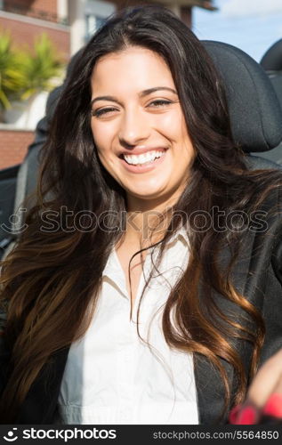 A young successful business woman in a luxurious convertible sports car