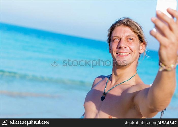 A young surfer taking his selfie on the beach. Nice day to remember