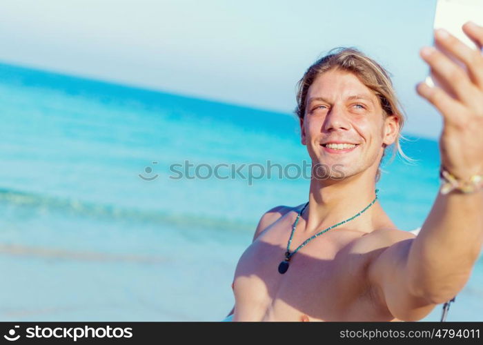 A young surfer taking his selfie on the beach. Nice day to remember