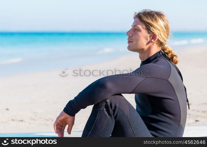 A young surfer with his board on the beach. Dreaming of the next big wave