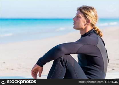 A young surfer with his board on the beach. Dreaming of the next big wave
