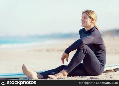 A young surfer with his board on the beach. Dreaming of the next big wave