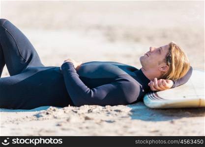 A young surfer with his board on the beach. I need some rest